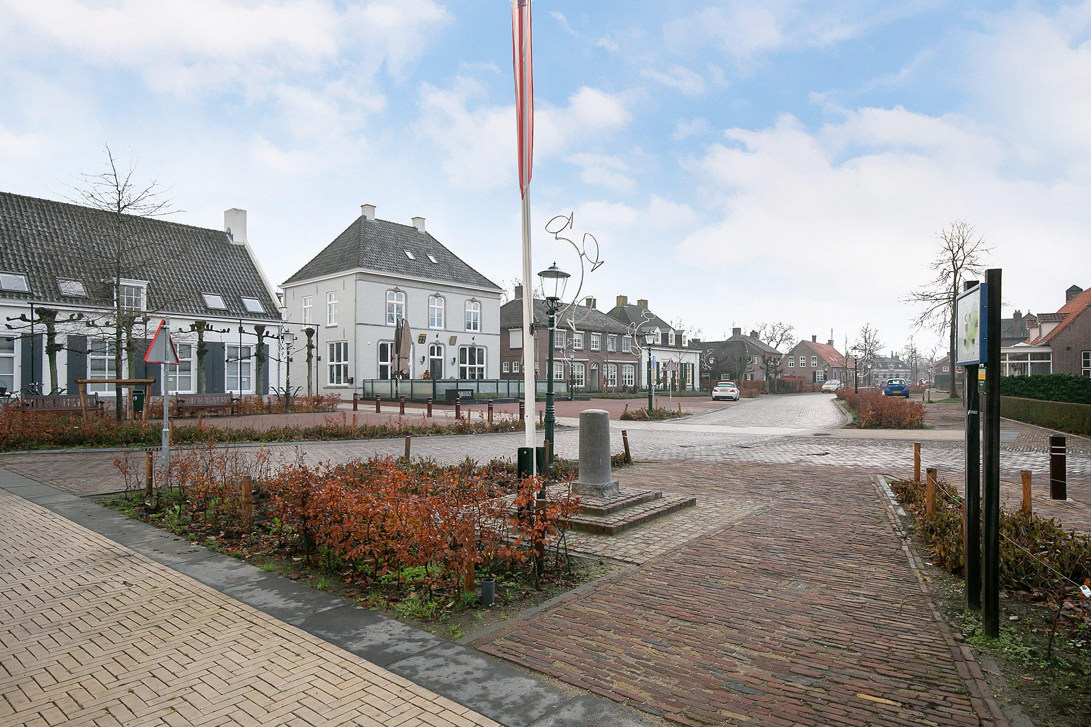 Dorpsplein met witte panden en een vlaggenmast
